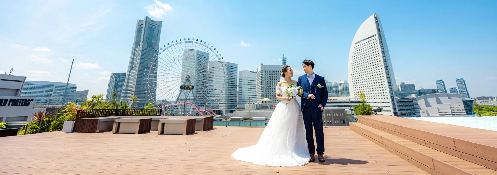 横浜のみなとみらいを背景に、屋上テラスで寄り添うウェディング姿の男女