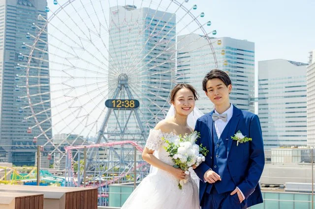 横浜のみなとみらいを背景に、観覧車の前で寄り添うウェディング姿の男女